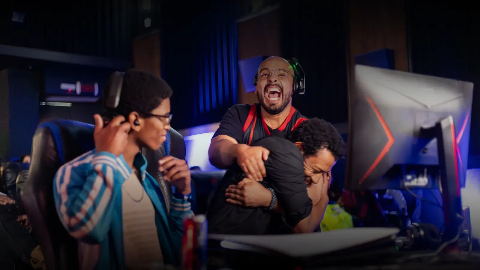 Players crowded around a monitor at a UGCZA event, reacting to a match.